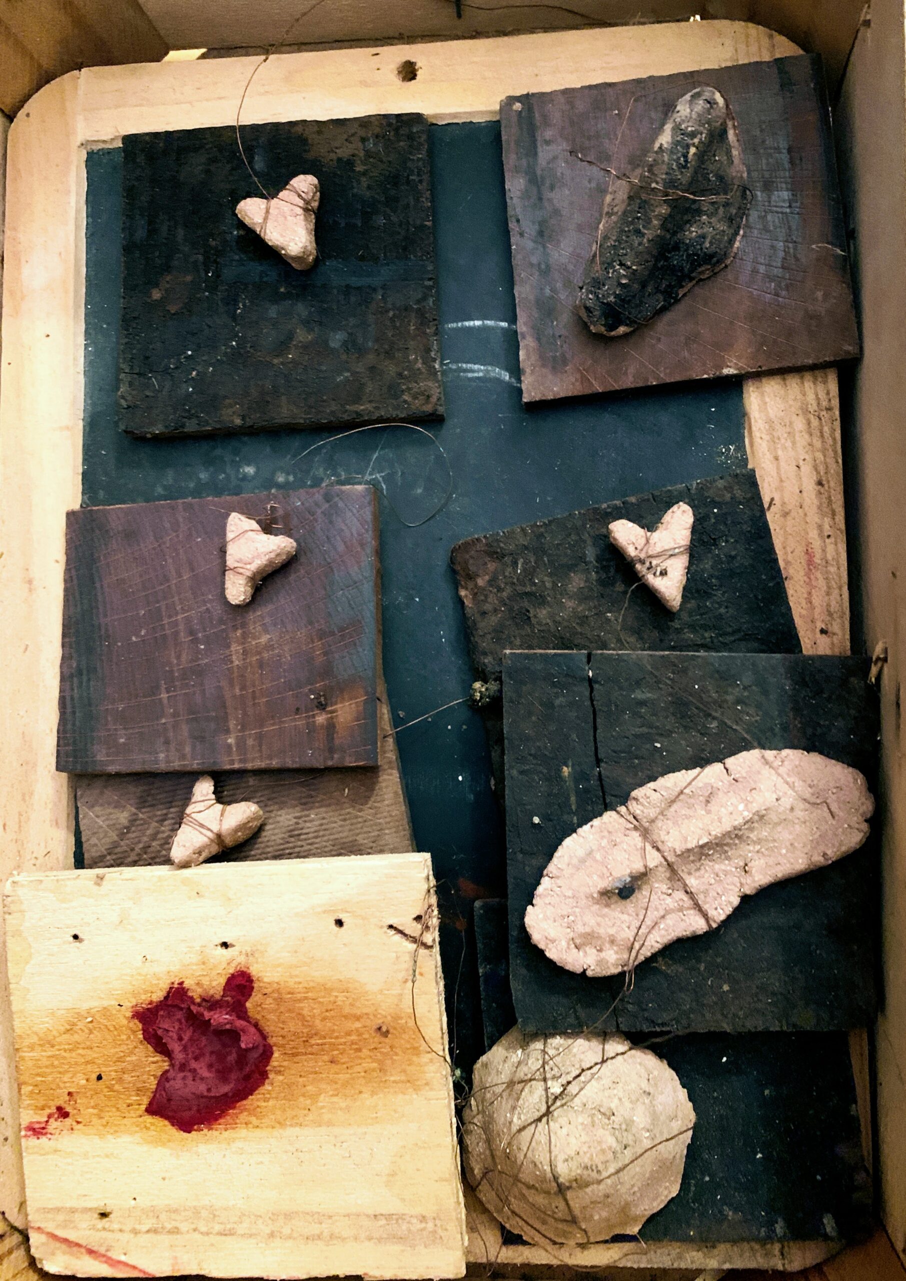 des petits éléments en céramique, liés avec du fil de cuivre a des supports en bois brûlés.