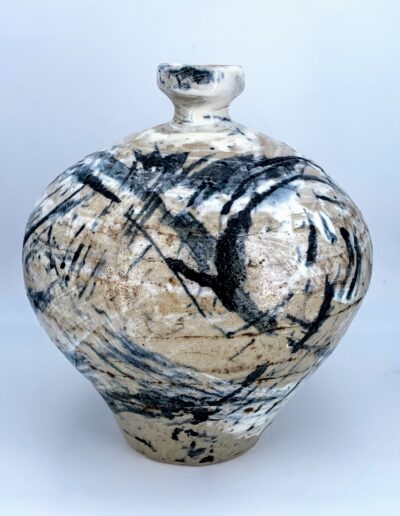 Grand vase en grès beige et blanc, de forme élancée, aux colombins visibles, décoré de motifs noirs et blancs au pinceau.